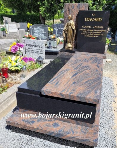 Nagrobek z Gnejsu i czarnego granitu, z figurką Maryi w kolorze złotym.